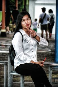 Portrait of young woman sitting on chair outdoors