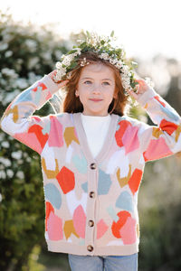 Happy smiling kid girl 6-7 year old wear knit colorful sweater wreath hairstyle with flowers