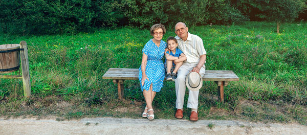 Portrait of family sitting on bench against plants