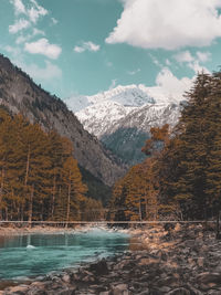 Scenic view of lake by snowcapped mountains against sky