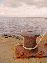 View of rusty metal by sea against sky