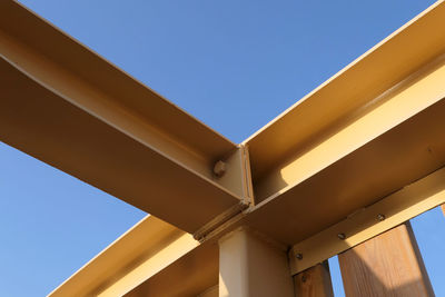 Metallic yellow beams against clear blue sky