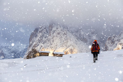 Rear view of man hiking on snow covered land