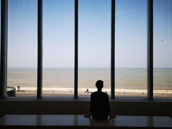 Rear view of man looking at sea against sky