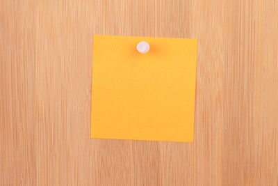Close-up of yellow paper on wooden surface
