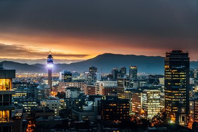 Illuminated cityscape against sky at dusk