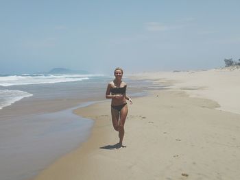 Full length of young woman running at beach
