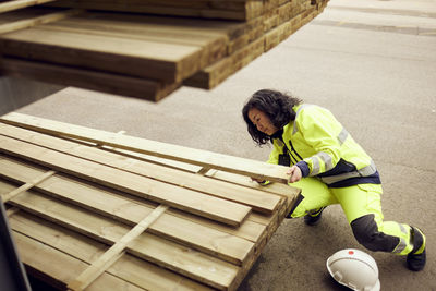 Mature female worker examining planks at lumber industry