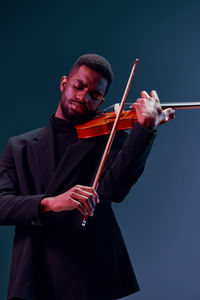 Midsection of man playing violin against clear blue sky