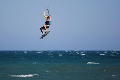 Full length of man kitesurfing over sea against sky