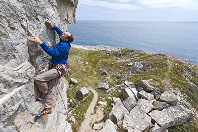 Man climbing on limestone cliff near the coast of swanage / uk