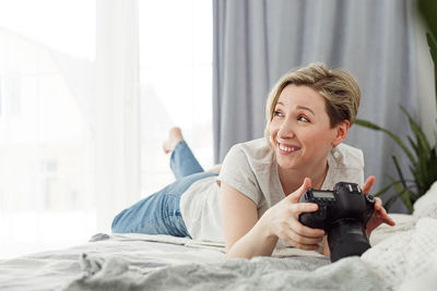 Portrait of a smiling young woman lying on bed