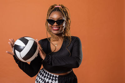 Portrait of young woman wearing sunglasses while standing against yellow background