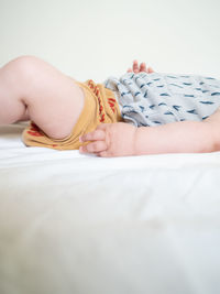 Midsection of baby lying on bed