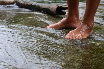 Low section of man standing in stream