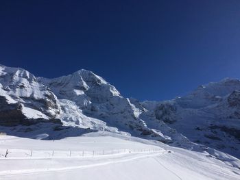 Scenic view of snowcapped mountains against clear blue sky