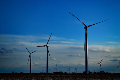 Low angle view of wind turbines on field