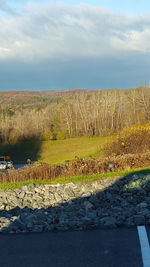 Scenic view of land by sea against sky