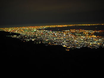 Illuminated cityscape against sky at night