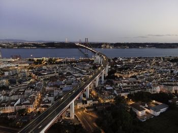 High angle view of illuminated city by sea against sky