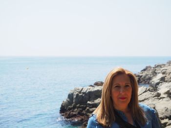 Portrait of young woman against sea against clear sky