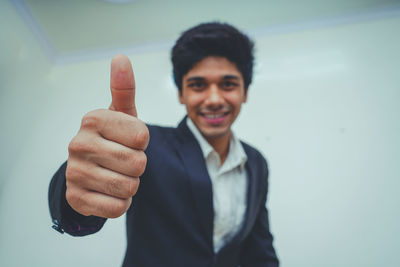 Portrait of smiling young man standing against wall