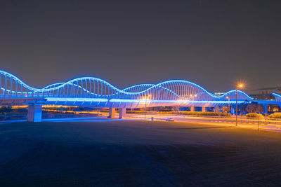 Light trails on bridge against sky at night