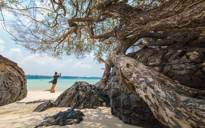 Traveller taking photo on rock by sea against sky