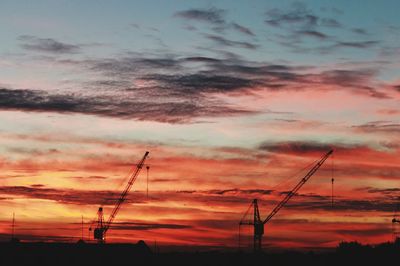 Silhouette electricity pylon against dramatic sky during sunset