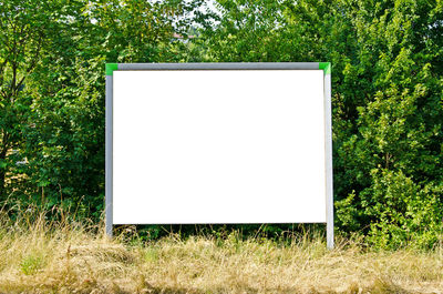 Empty chair on field against trees