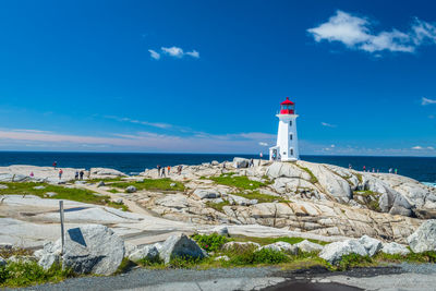 Lighthouse by sea against blue sky