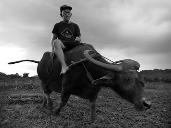 Man riding horse on field against sky