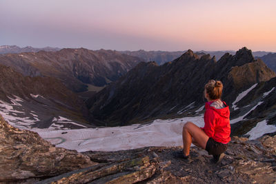 Rear view of woman crouching on cliff