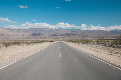 Road by desert against sky