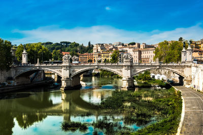 Bridge over river in city against sky