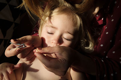 Close-up of woman cutting girl nail