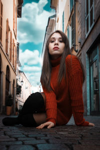 Beautiful young woman sitting in city