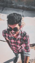 High angle portrait of young man wearing sunglasses standing outdoors