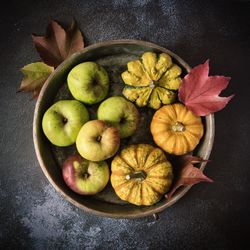 Apples and small pumpkins in an old rustic bowl