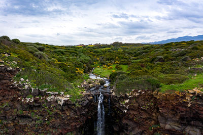 Scenic view of waterfall against sky