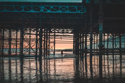 Underneath view of pier in sea during sunset