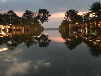 Reflection of silhouette trees in water against sky