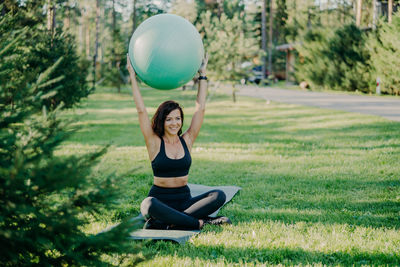 Full length of woman exercising with fitness ball at park