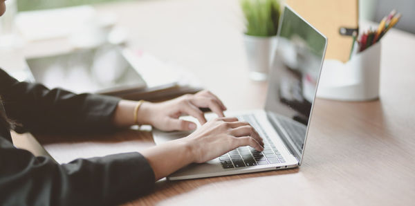 Midsection of woman using laptop on table