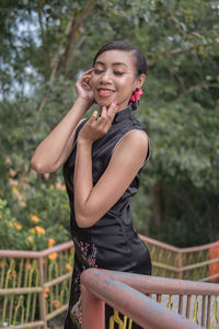 Portrait of young woman standing against railing