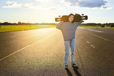 Rear view of woman walking on road against sky during sunset