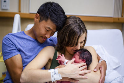 Tender new parents lovingly hold their newborn in a hospital bed
