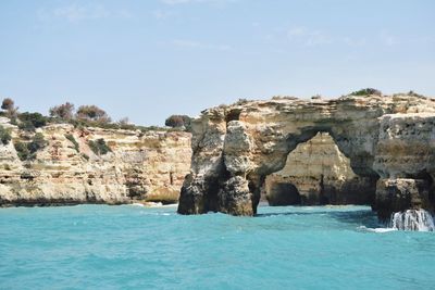 Rock formations at sea against sky