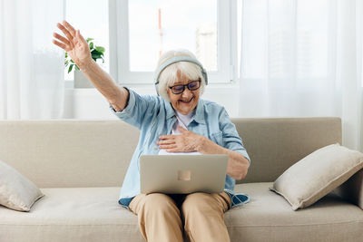 Young woman using laptop while sitting on sofa at home