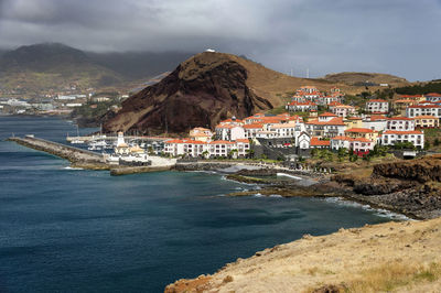 View of camara de lobos by sea against cloudy sky